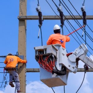 Electricians with disconnect stick and boom lift are installing electrical system on power pole and using protection relay